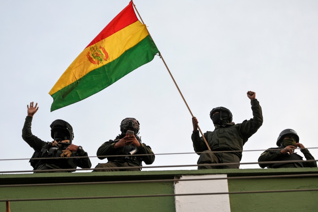 Police officers wave a national flag while standing on the roof of their headquarters in Cochabamba, Bolivia. Photo: Reuters