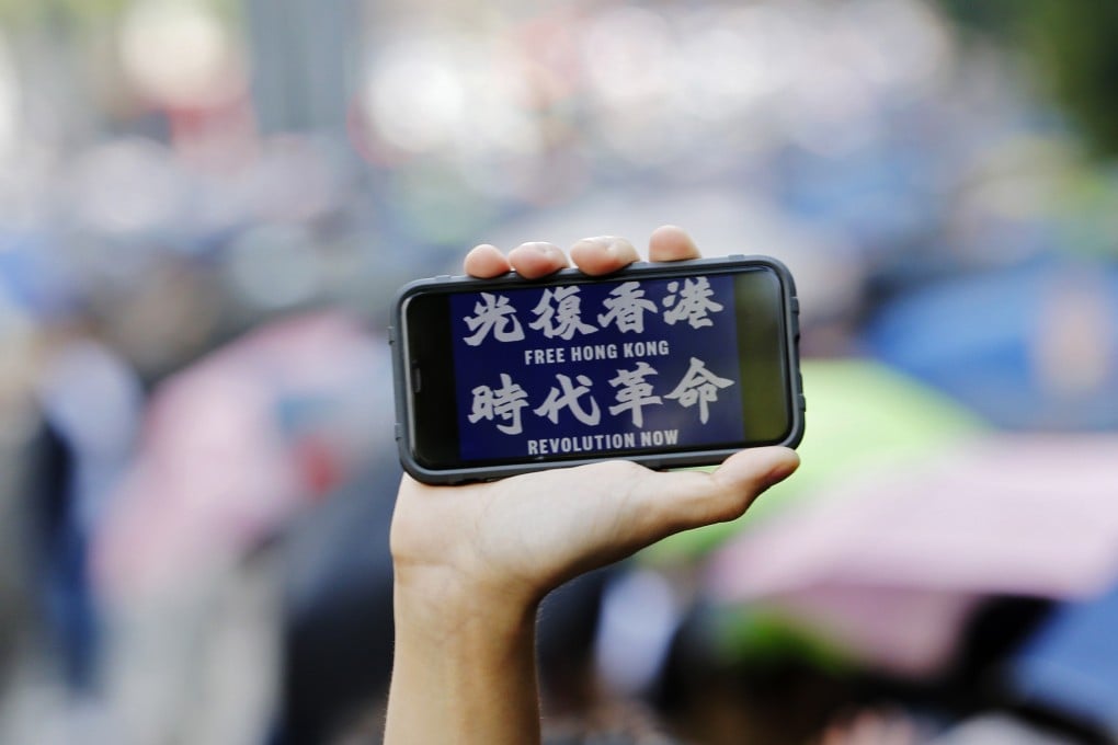 A protester holds up a mobile phone showing the words “Free Hong Kong, revolution now” during an October 20 rally against a recent ban on face masks. Photo: EPA-EFE