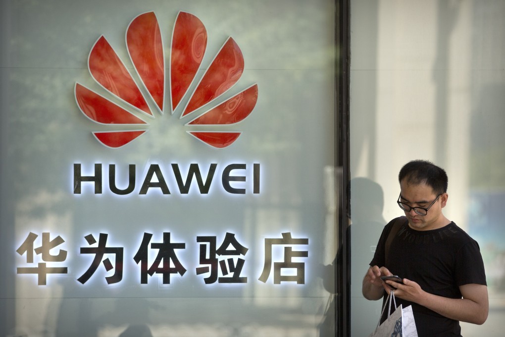 A man uses his smartphone outside of a shop selling Huawei products at a shopping mall in Beijing. Photo: AP