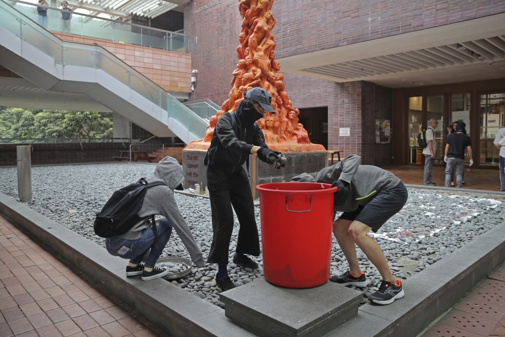 Students collect stones to be thrown at police near the Pillar of Shame, a sculpture at the University of Hong Kong, on November 12. Photo: AP