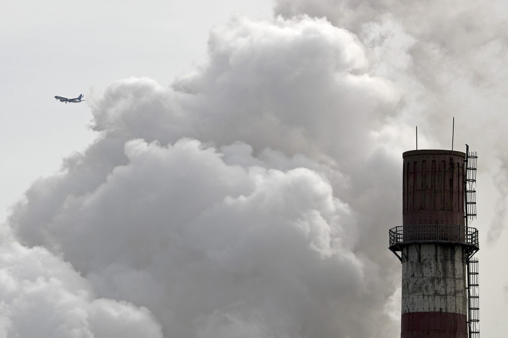 A passenger airliner flies past smoke emitted from a coal-fired power plant in Beijing in 2017. Photo: AP