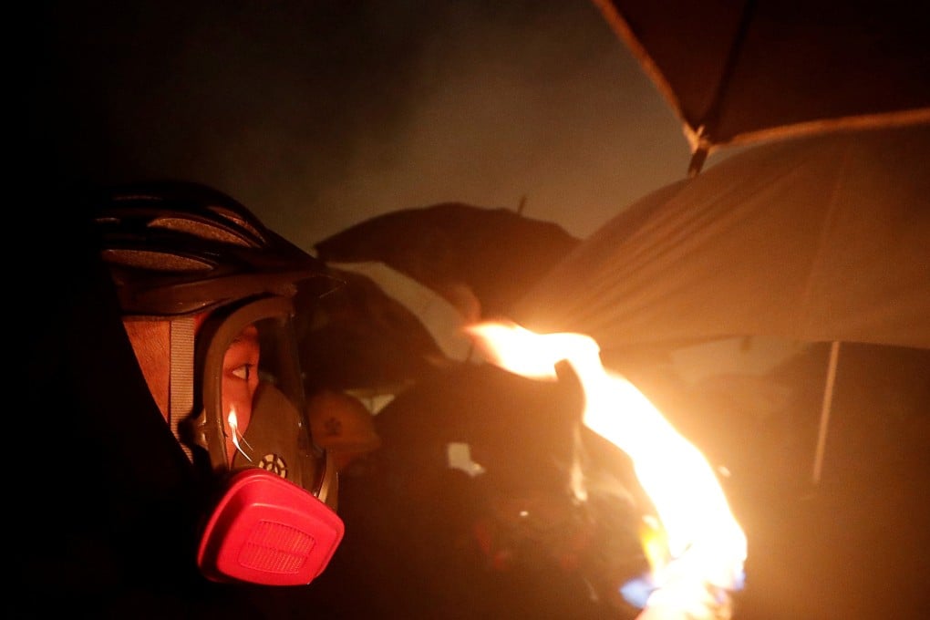 A protester, wearing a tear-gas mask, is engaged in a stand-off with riot police at the Chinese University of Hong Kong on Tuesday night. Photo: Reuters
