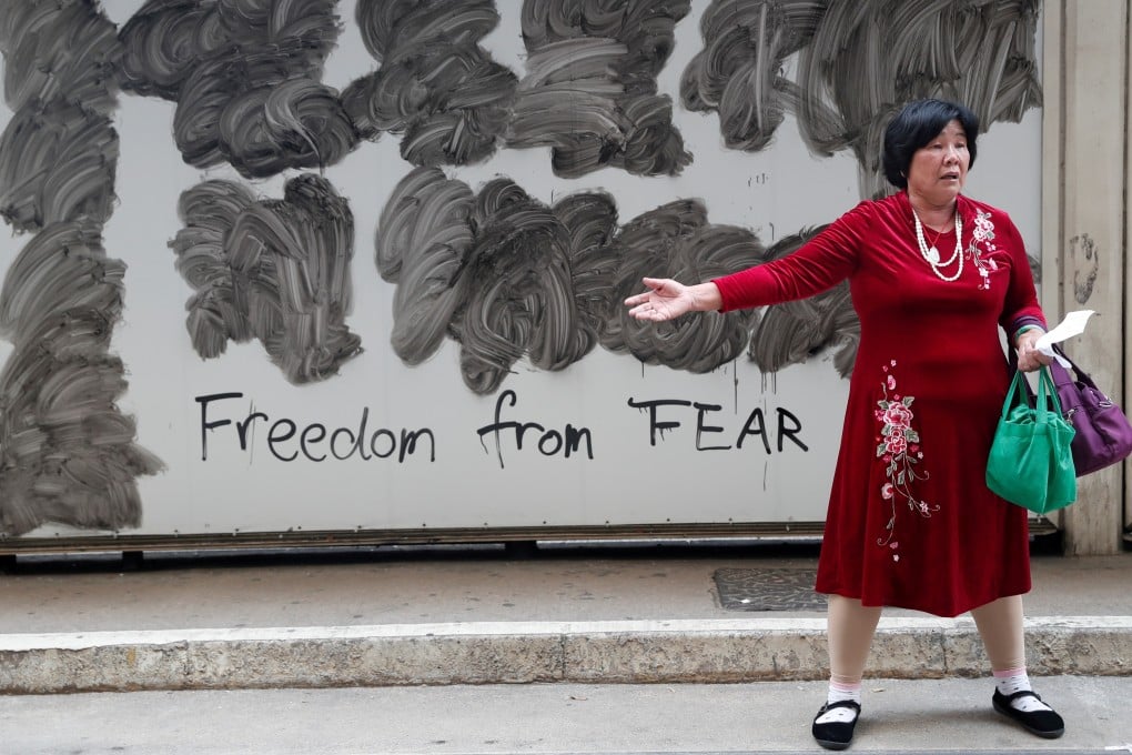 A woman stands in front of graffiti left behind by protesters following an anti-government demonstration in Central on November 13. Photo: Reuters
