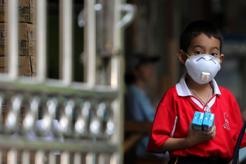 A student wears a mask to guard against air pollution as he waits to be picked up at the gate of a public school in Bangkok. Photo: Reuters
