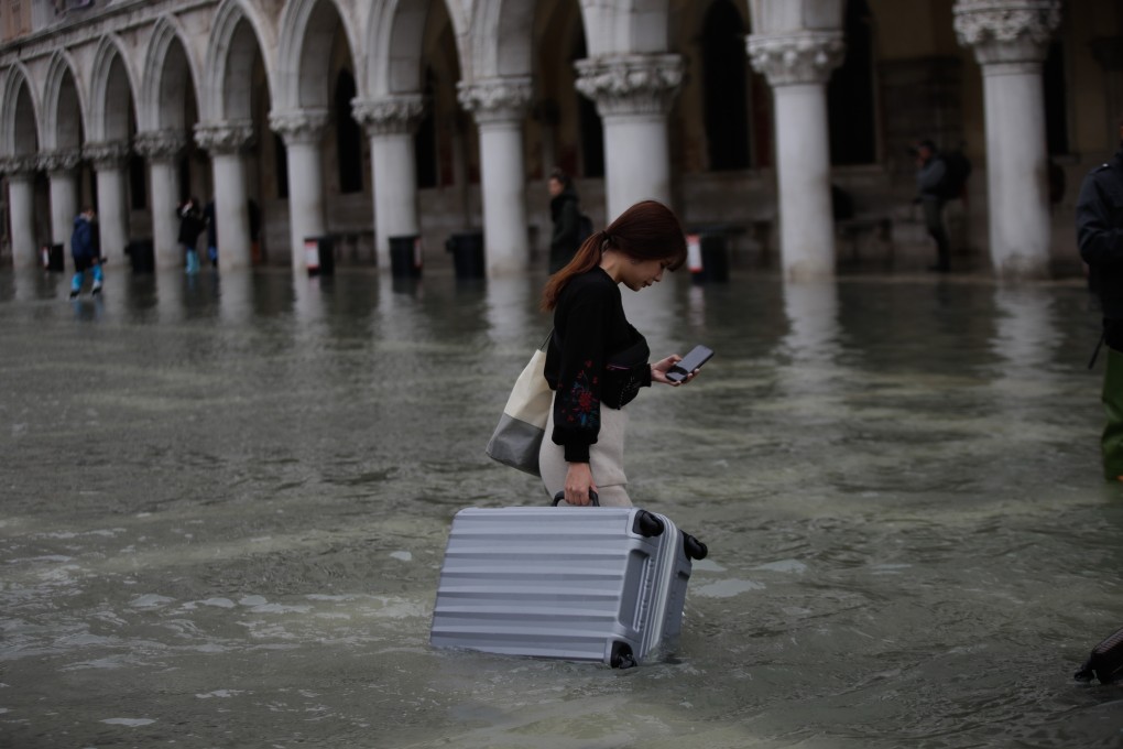 A tourist woman walks across the flooded San Marco Square in Venice. Photo: Xinhua