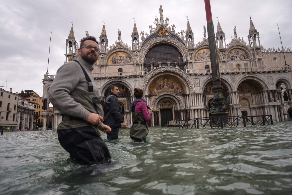 People walk across the flooded St Mark’s Square by St Mark’s Basilica in Venice. Photo: AFP