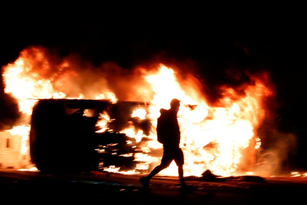 A protester walks past a burning vehicle in Hong Kong. Photo: Reuters