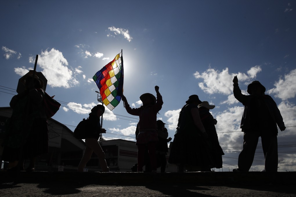 A supporter of former President Evo Morales waves a Whipala flag as he blocks the highway to access the "Yacimientos Petroliferos Fiscales Bolivianos" plant in El Alto, Bolivia. Photo: AP Photo