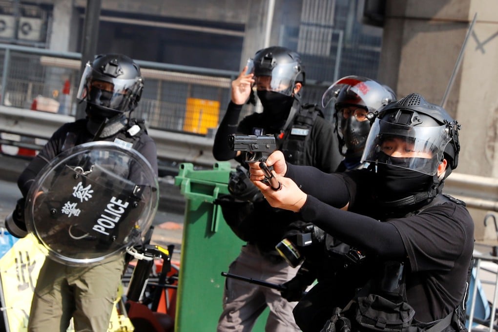 A riot police officer points a gun at protesters attempting to escape the Polytechnic University campus, during clashes in Hung Hom on November 18. Photo: Reuters