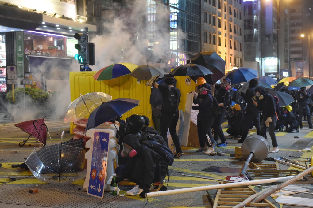 Protesters take cover behind barricades as police fire tear gas during clashes in the Jordan district of Hong Kong on November 18, 2019. Photo: EPA-EFE