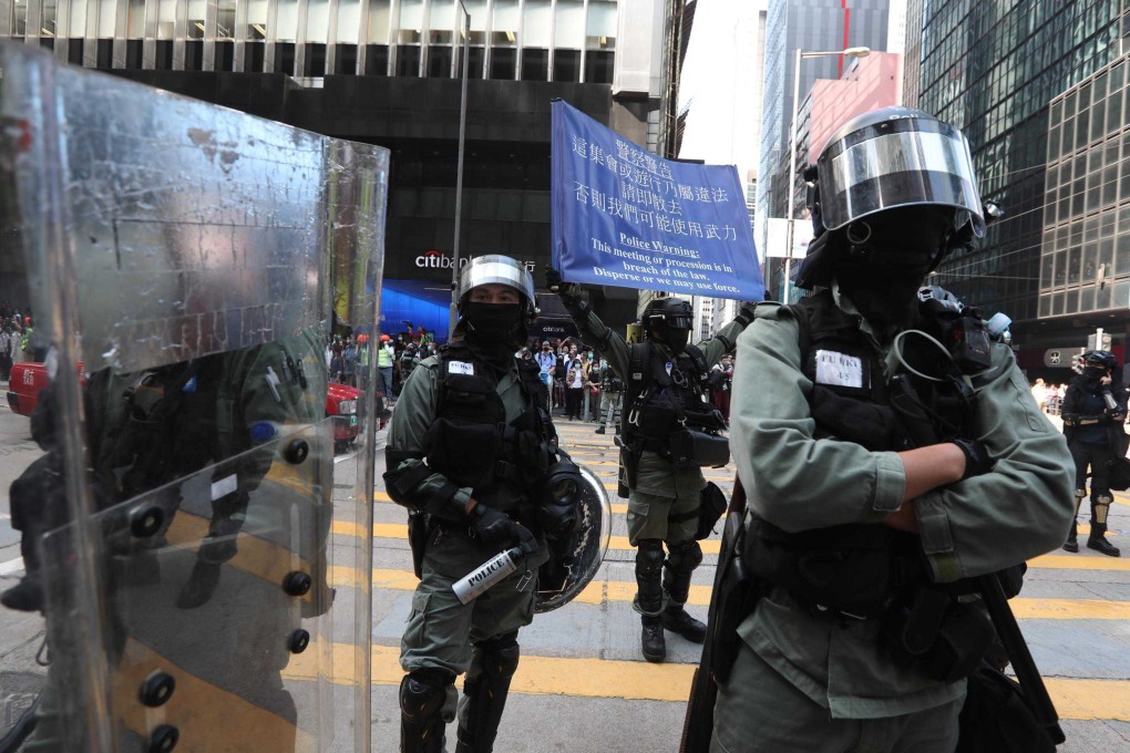 Riot police raise a blue flag warning protesters in Central that their rally is illegal. Photo: Xiaomei Chen