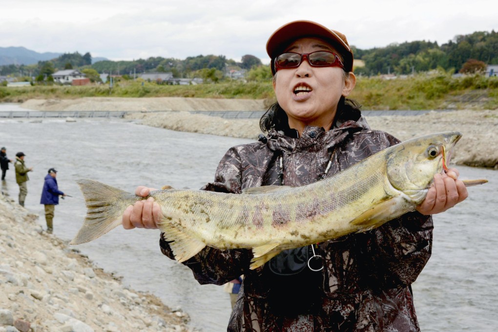 An angler shows off a salmon caught in the Kido River in Naraha, Fukushima prefecture. Photo: Kyodo