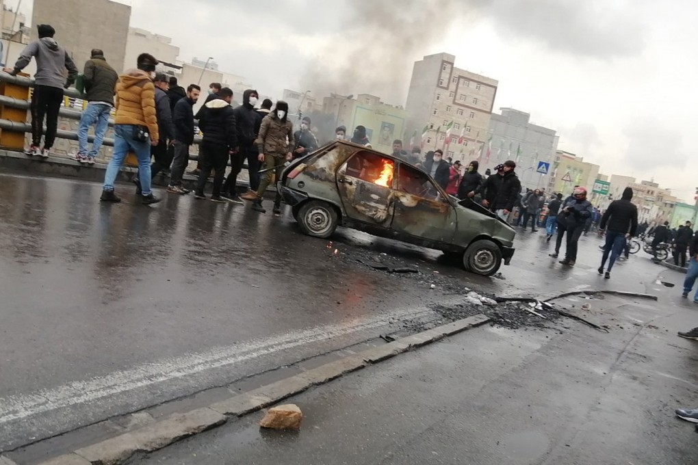 Iranian protesters stand around a vehicle set ablaze during clashes following fuel price increase in Tehran. Photo: EPA-EFE