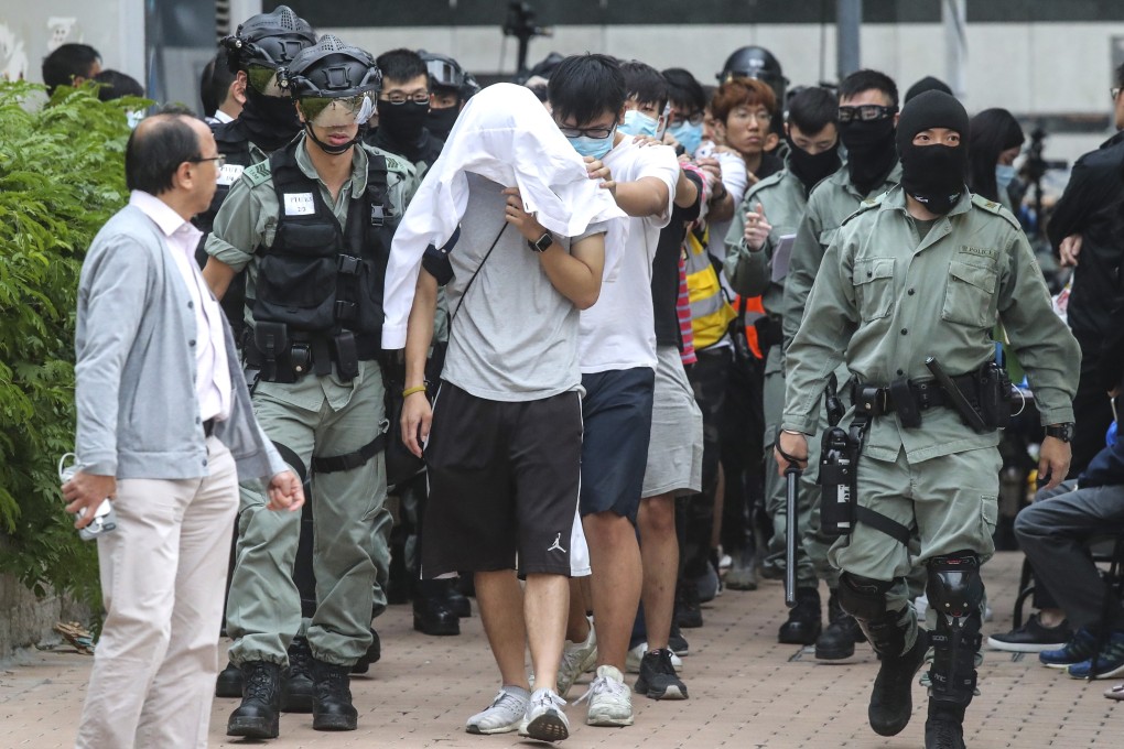 Protesters who have surrendered after a siege at Polytechnic University in Hung Hom are escorted away by police officers. Photo: K. Y. Cheng