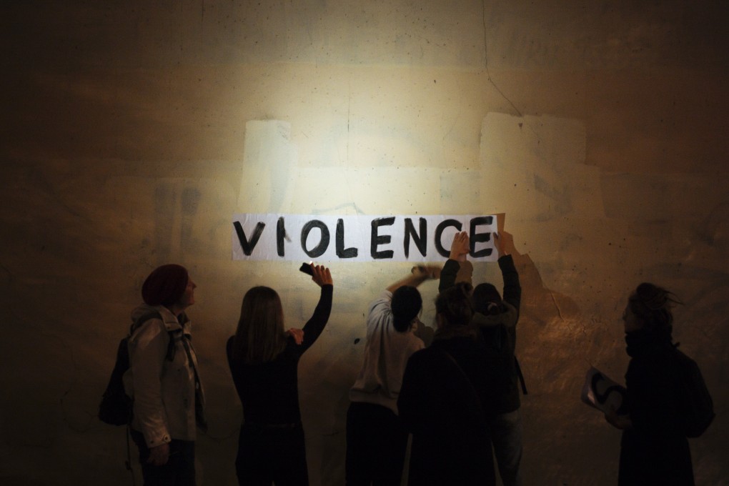 The word "violence" is pasted onto a wall by a group of women in a dark street in Paris. Photo: AP