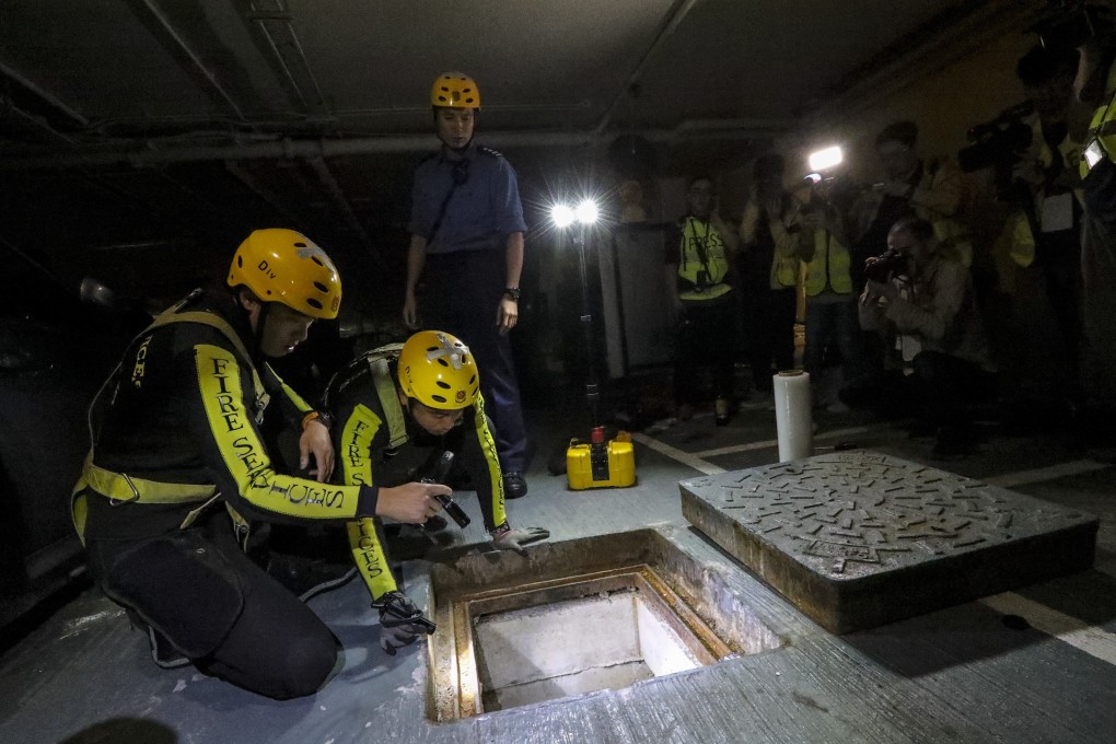 Firefighters look down a manhole to see whether any protesters have tried to escape through it. Photo: Felix Wong
