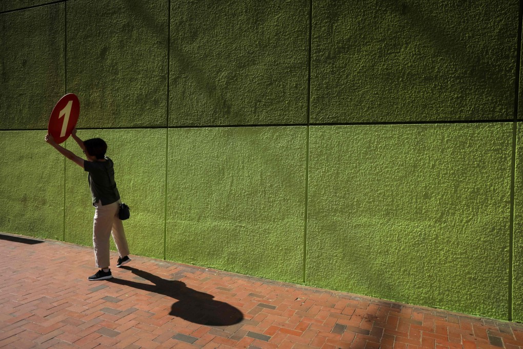 A political campaigner holds up a sign to arriving voters during the district council elections in North Point in Hong Kong on Sunday. Photo: AFP