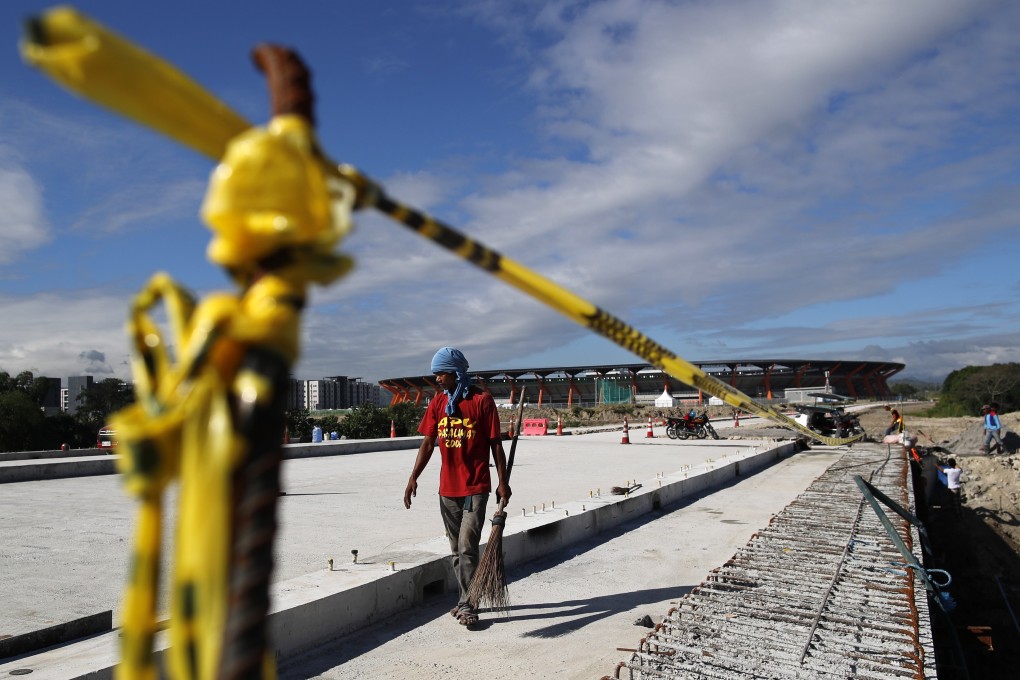 A Filipino worker walks along an unfinished road leading to the aquatics centre to be used in the SEA Games. Photo: EPA