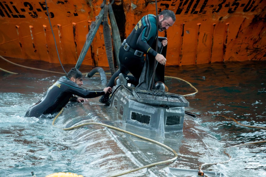 Spanish Civil Guard divers stand over the refloated prow of a submarine used to transport drugs illegally in Aldan, northwestern Spain, on Tuesday. Photo: AFP