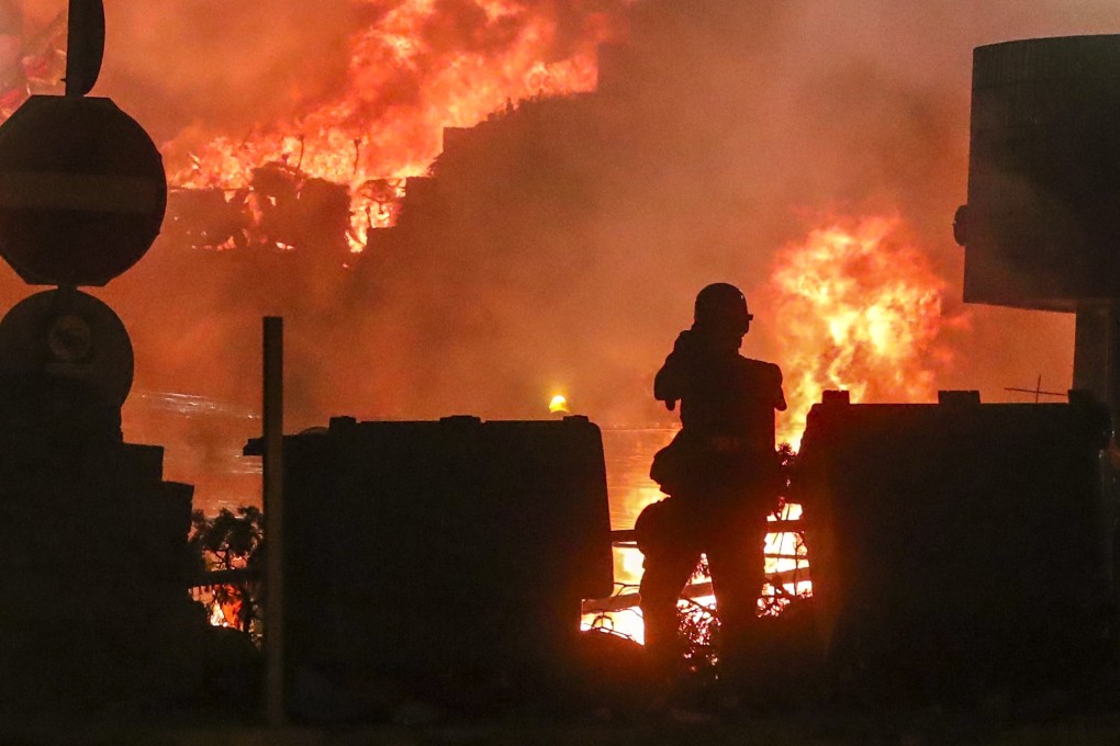 A lone protester watches as fires rage around Polytechnic University during clashes with police. Photo: Sam Tsang