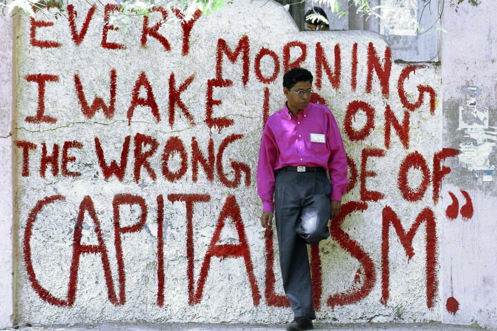 A college student leans against a wall painted with anti-capitalism graffiti in Mumbai, India, in 2004. Photo: AFP