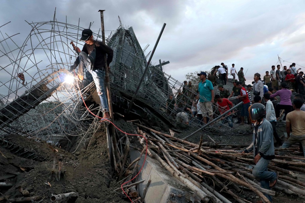 A man cuts through metal reinforcements as rescuers search for victims at a construction site in Siem Reap on Monday. Photo: AFP