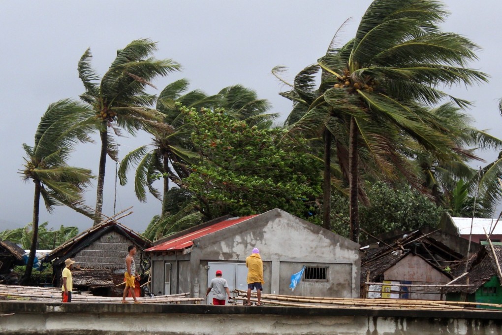 Villagers look on as strong winds blow trees next to houses in the town of Calabanga, Camarines sur province, Philippines, ahead of Typhoon Kammuri. Photo: EPA-EFE