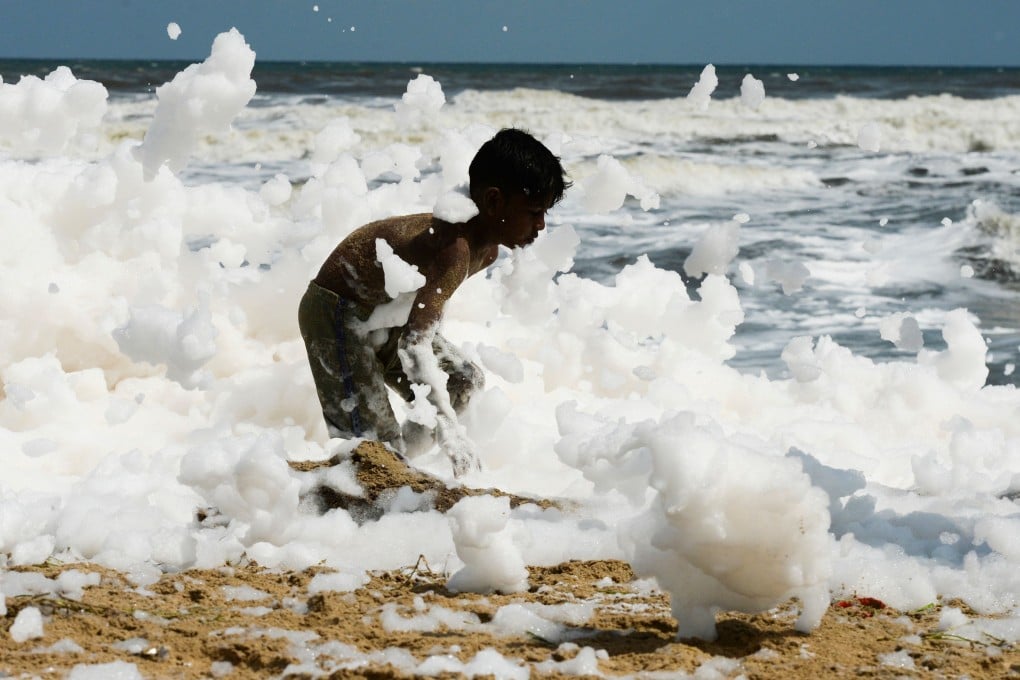 A child plays in a foamy discharge, caused by pollutants mixed with sea water, in the surf at a beach in Chennai, India. Photo: AFP