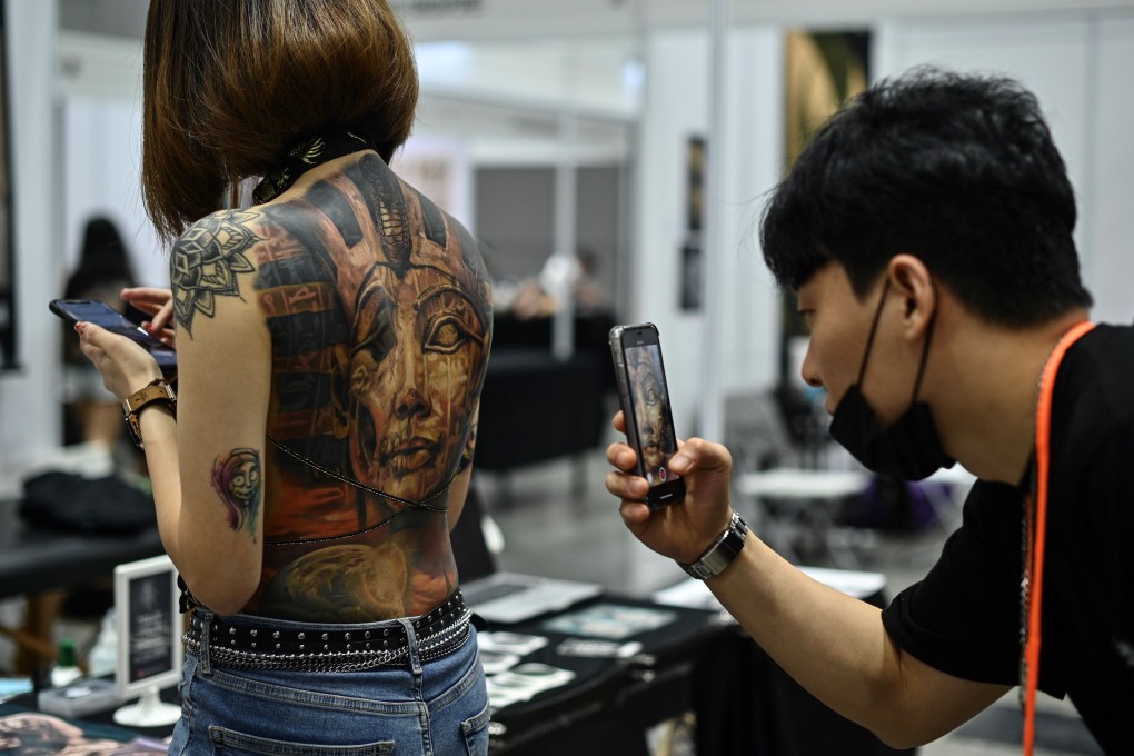 A man takes pictures of a woman with tattoos during the International Malaysia Tattoo Expo in Kuala Lumpur. Photo: AFP