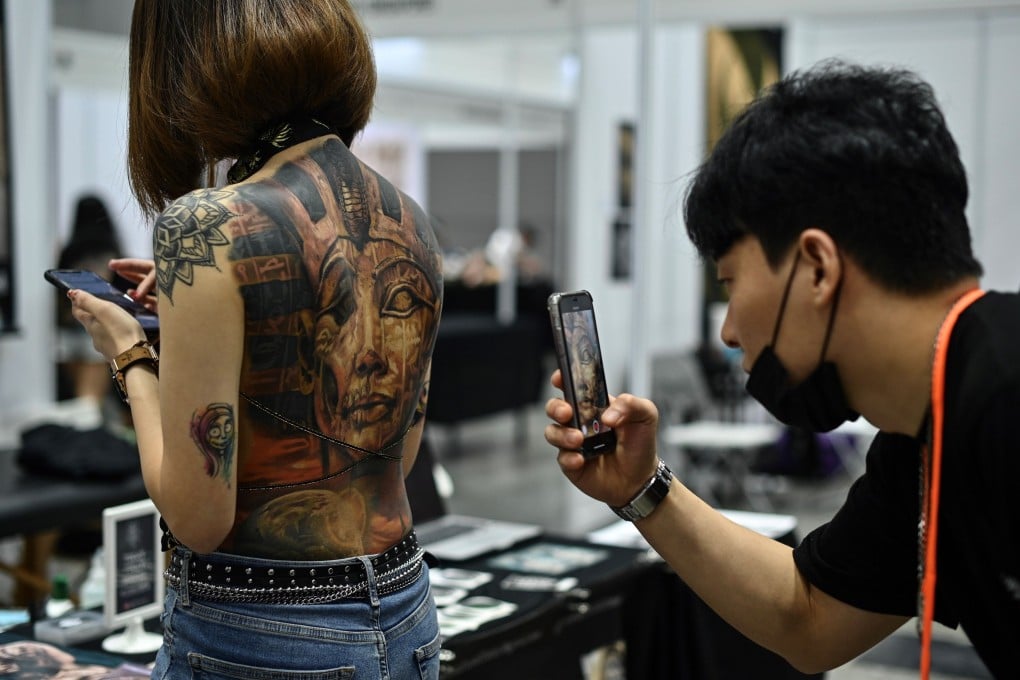 A man takes pictures of a woman with tattoos during the International Malaysia Tattoo Expo in Kuala Lumpur. Photo: AFP