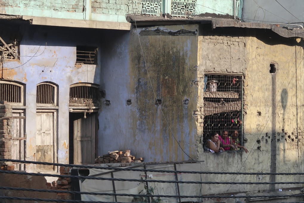 Three sex workers peer through a window as they wait for customers in the notorious red light district at Garstin Bastion Road, New Delhi. Photo: Shoaib Shafi
