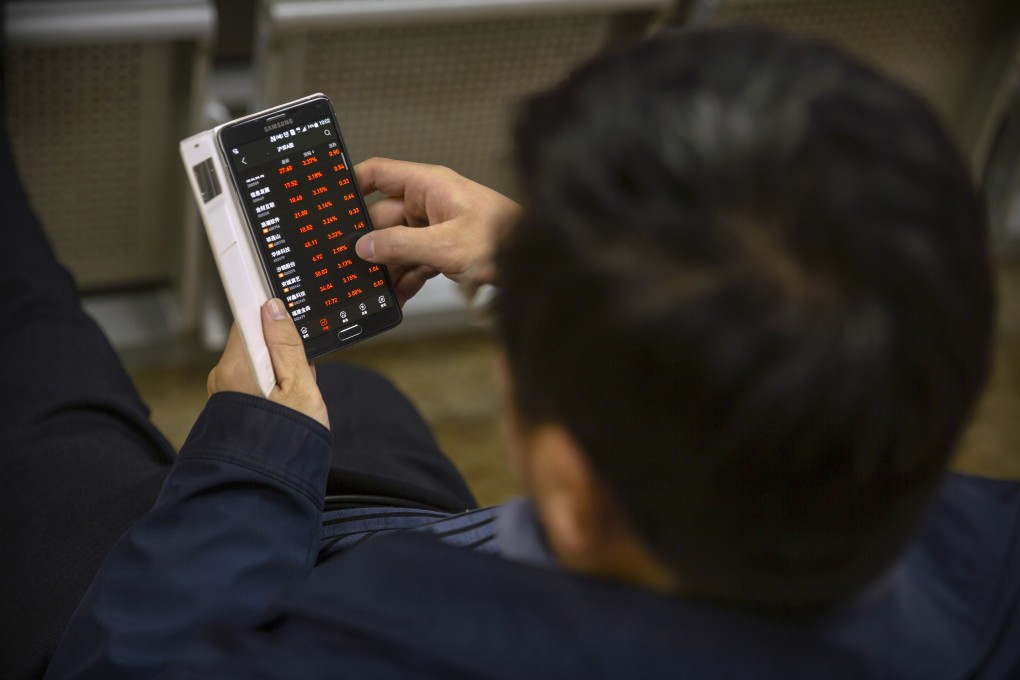 A Chinese investor uses a smartphone to monitors stock prices at a brokerage house in Beijing. Photo: Associated Press