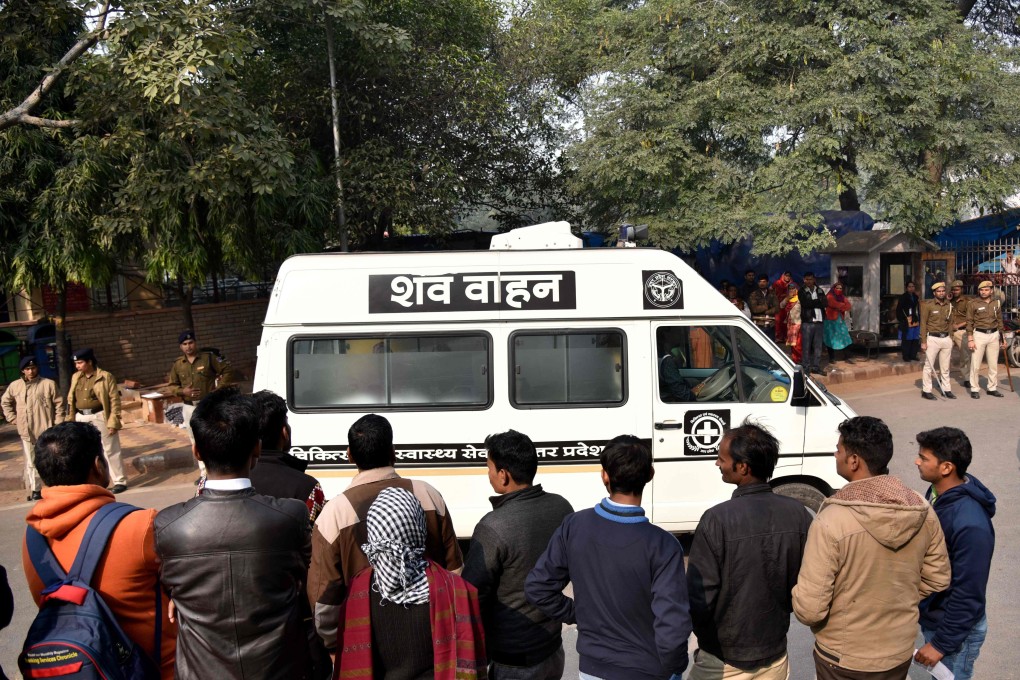 Bystanders look on as the body of the Unnao rape victim is transported in an ambulance from a hospital in New Delhi to her village. Photo: AFP