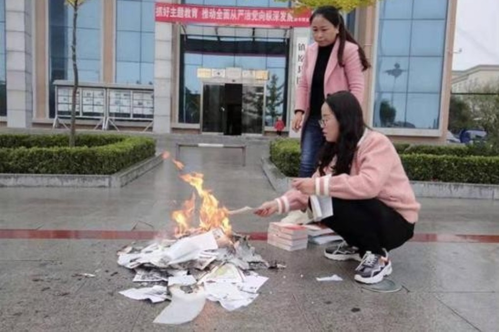 The report included a photo of two employees burning books in front of the public library in Zhenyuan, Gansu province. Photo: Handout