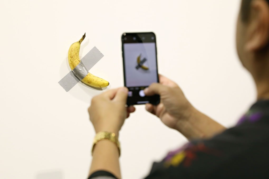 A visitor takes a photo of Maurizio Cattelan's “Comedian” at Art Basel Miami on Friday. Photo: AFP