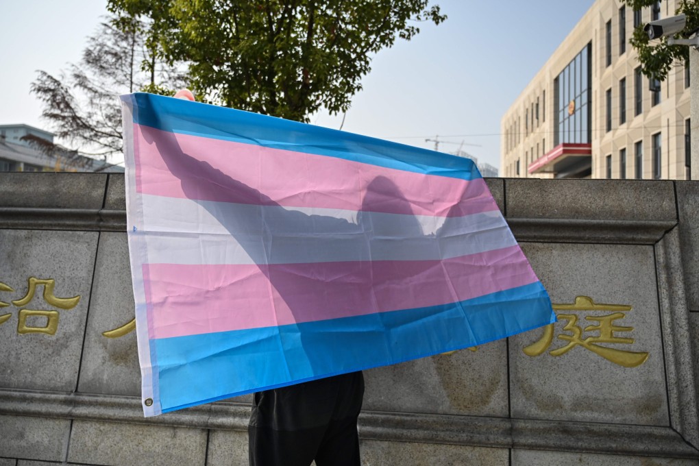 Yang poses with a transgender pride flag outside the court in Hangzhou. Photo: AFP