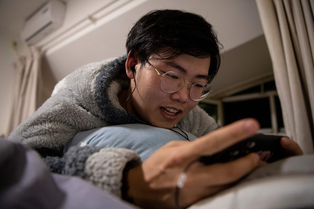 Zhuansun Xu, 22, talking to a girlfriend on his phone while playing a mobile game in his room in Beijing. A foreign exchange trader by day, he is a “virtual boyfriend” by night, chatting with female clients. Photo: AFP