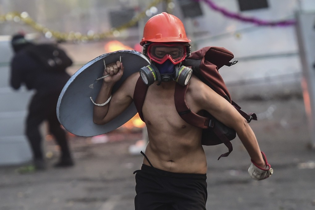 A demonstrator wearing a helmet runs with a makeshift shield during a protest in Santiago. Photo: AFP