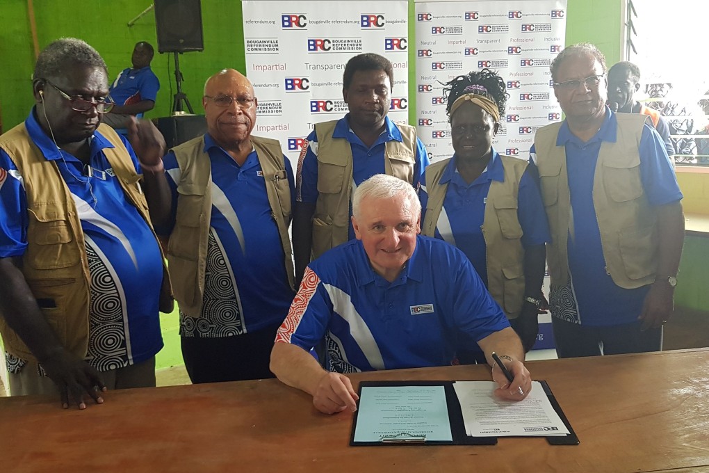 Bougainville Referendum Commission Chairman Bertie Ahern (centre) signs the referendum results announcement in Bougainville on Wednesday. Photo: AFP