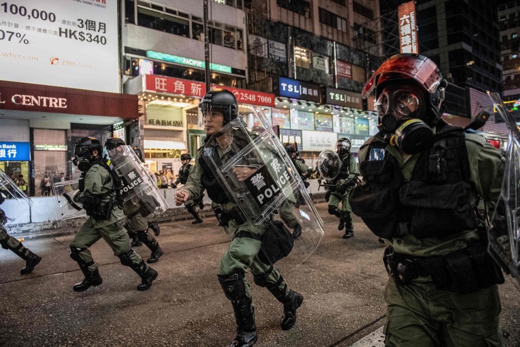 Riot police run towards protesters on Nathan Road in Hong Kong on December 1. Photo: AFP