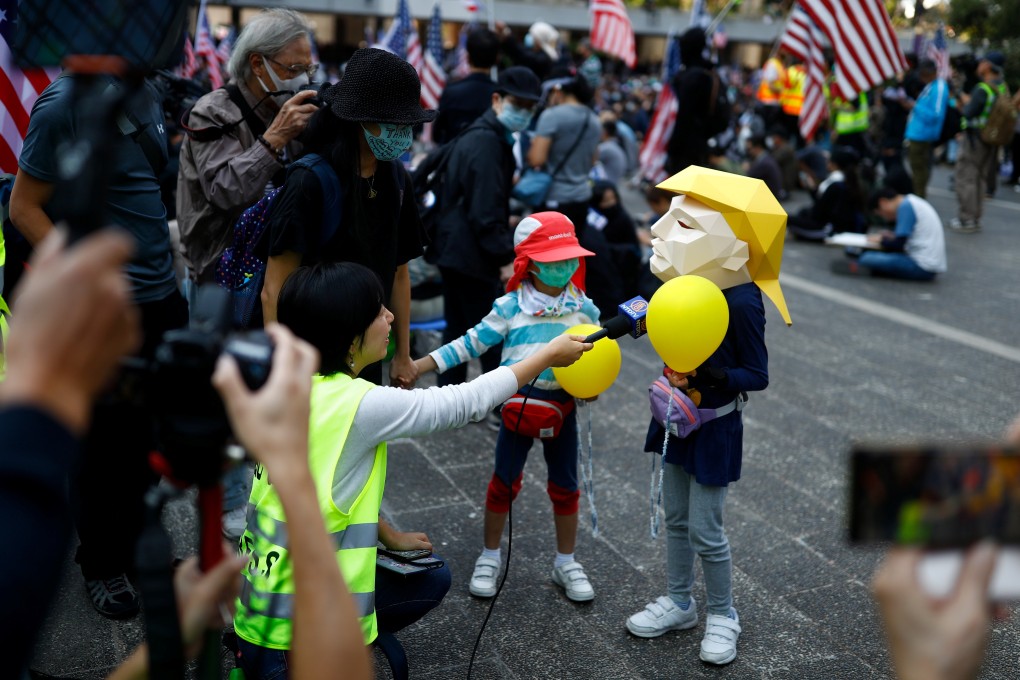 A child wearing a mask of US President Donald Trump is interviewed during a “march of gratitude” to the US consulate in Hong Kong on December 1. Although the anti-government movement has been marred by violence, it has also shown tremendous creativity. Photo: Reuters