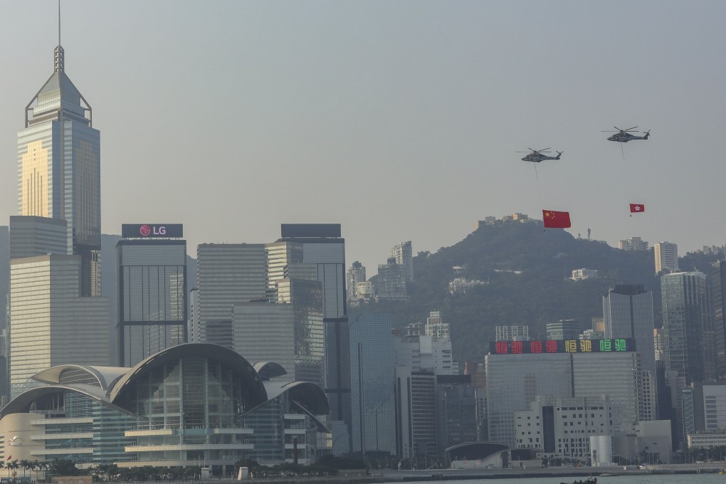 Two Government Flying Service helicopters carry the national flag of the People's Republic of China (left) and the Hong Kong flag (right) over Victoria Harbour in Hong Kong. Photo: K.Y. Cheng