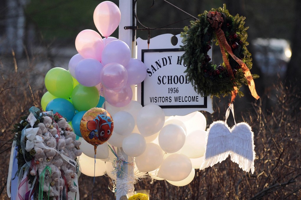 Flowers, teddy bears, candles, balloons and a pair of angel wings left by mourners are seen at the Sandy Hook Elementary School sign. Photo: TNS
