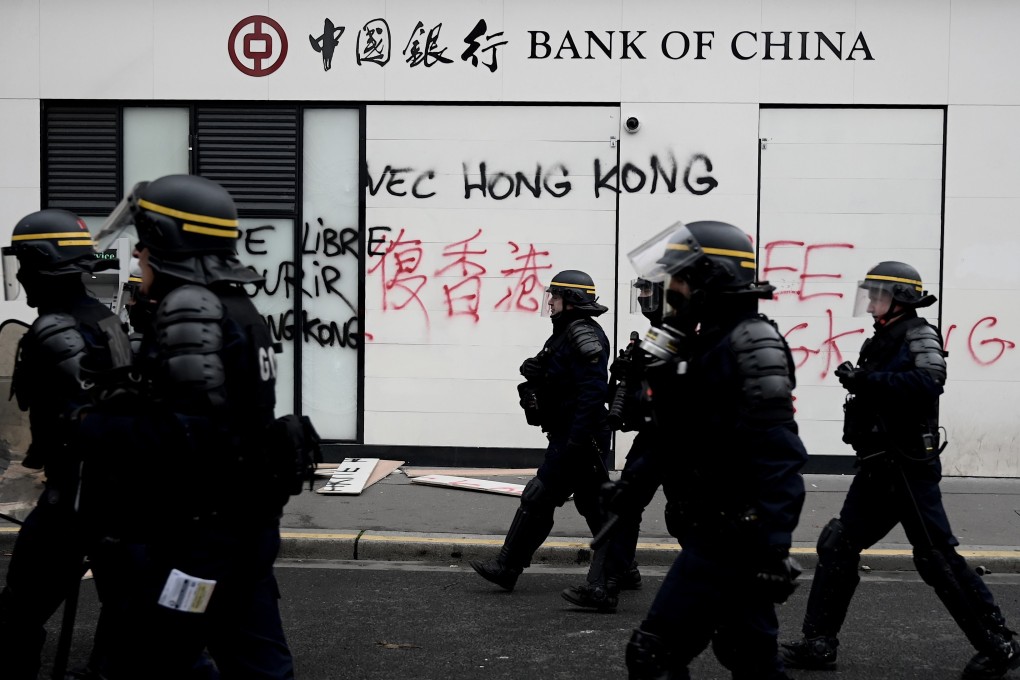 Hong Kong riot police officers walk past a Bank of China branch which has been vandalised by anti-government protesters. Photo: AFP