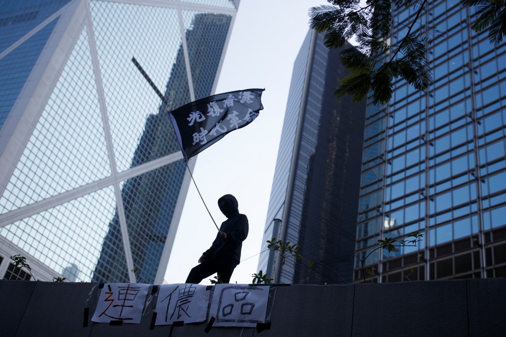 A protester waves a flag reading "Reclaim Hong Kong, Revolution of our Time" during an anti-government protest in the Central district of Hong Kong. Photo: Reuters