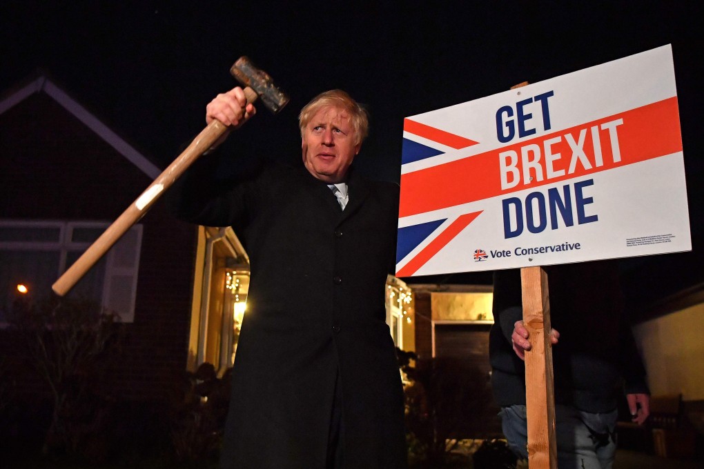 Britain's Prime Minister Boris Johnson poses with a hammer and a sign. Photo: AFP