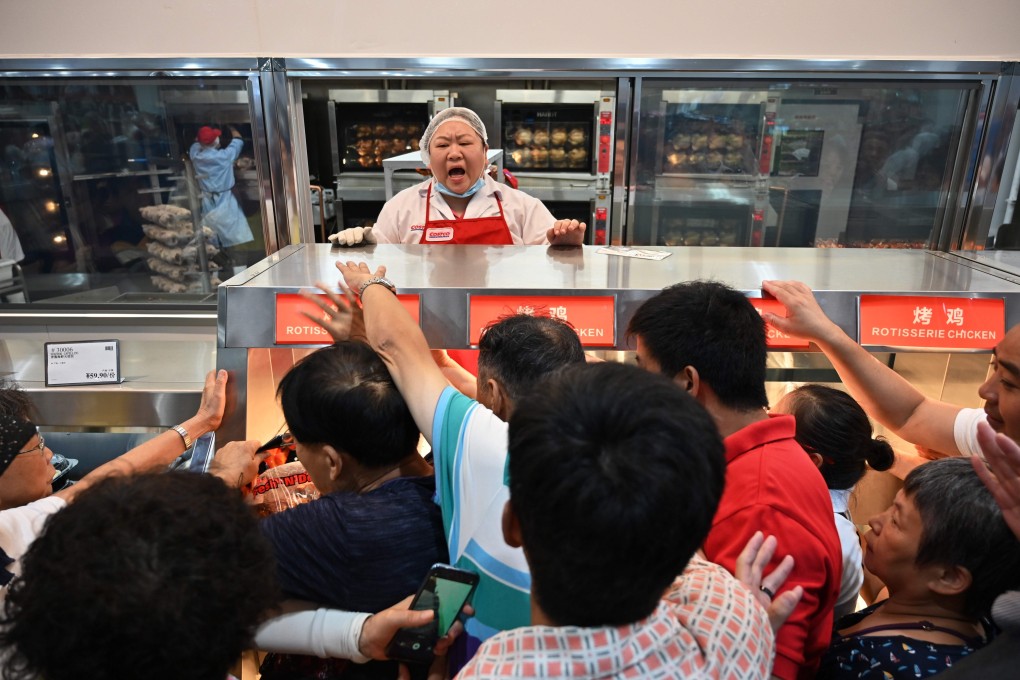 People try to buy a roast chicken at a Costco store in Shanghai, the first in China, on its opening day on August 27. Consumers in both the US and China would benefit from a reduction of trade frictions between the two countries. Photo: AFP