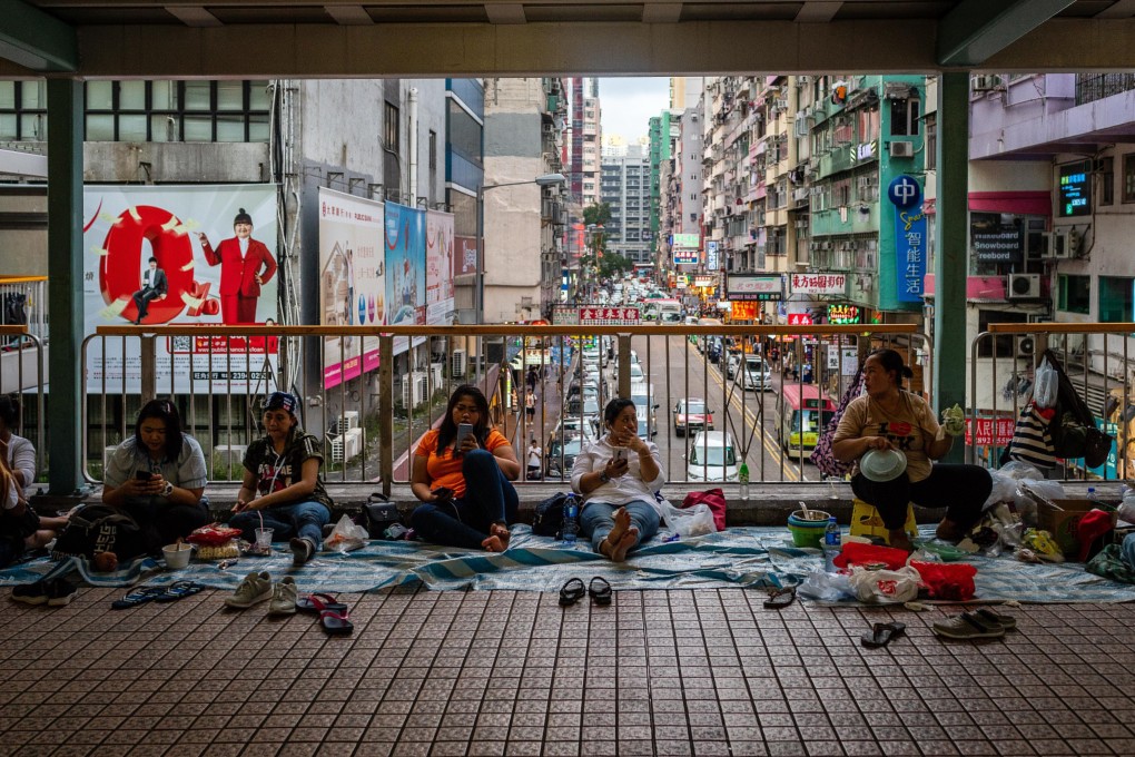 Domestic helpers spend their weekly day off on a footbridge in Mong Kok. Photo: Bloomberg