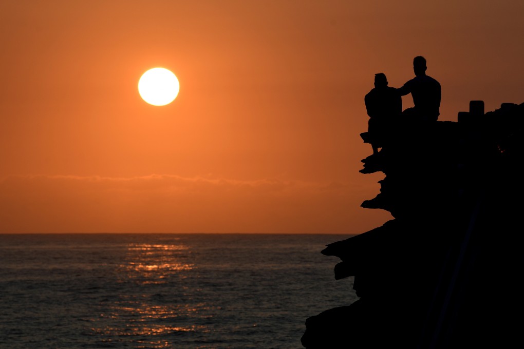People watch the sunrise at Bronte Beach Pool in Sydney on Wednesday. Photo: EPA