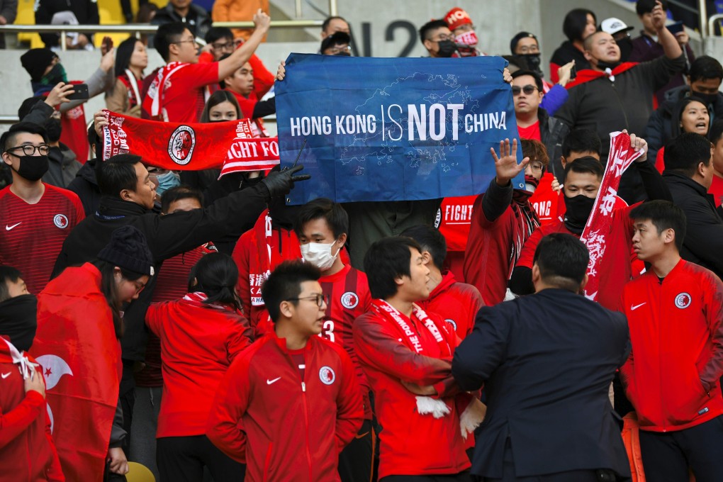 Hong Kong supporters hold a banner reading “Hong Kong is not China" as security members try to take it away match between Hong Kong and China in Busan. Photo: AFP